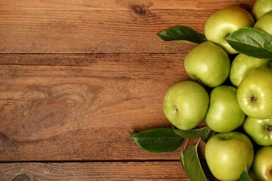 Photo of Ripe green apples with leaves on wooden table, flat lay. Space for text