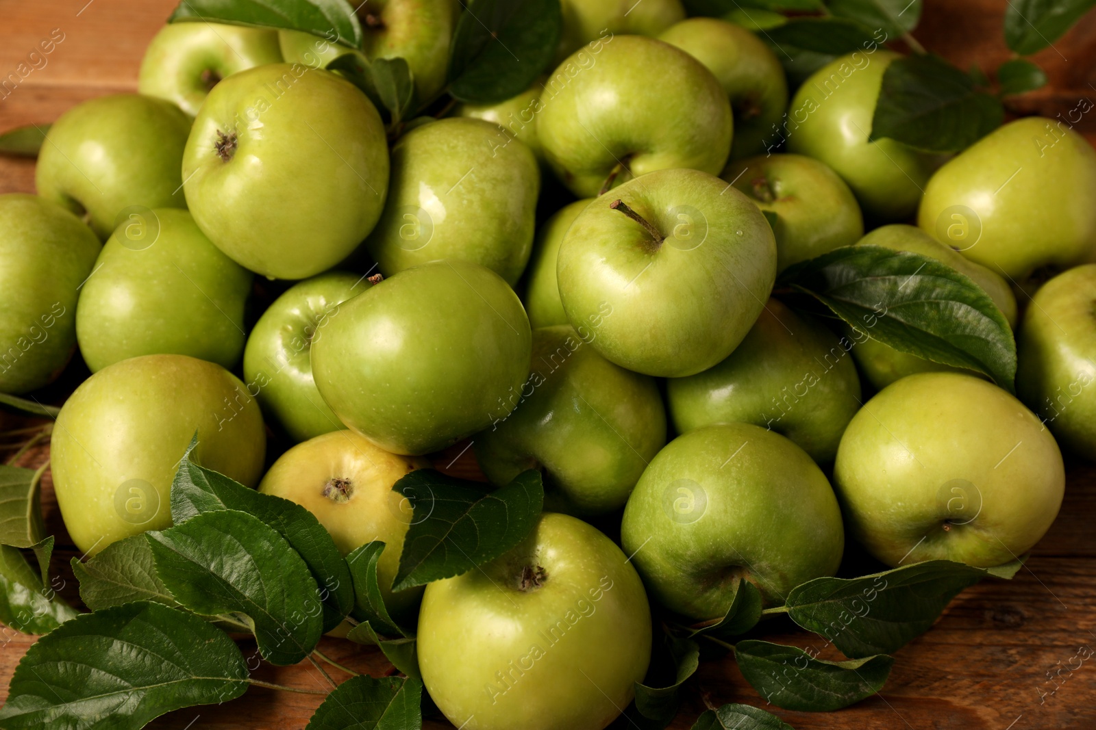 Photo of Ripe green apples with leaves on wooden table