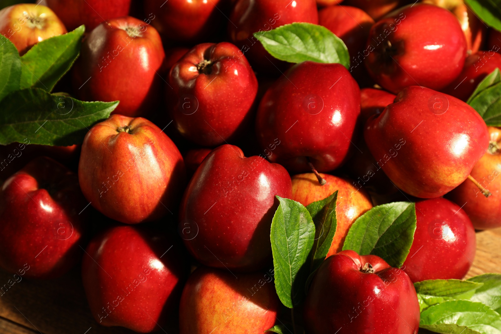 Photo of Fresh ripe red apples and green leaves on wooden table, closeup