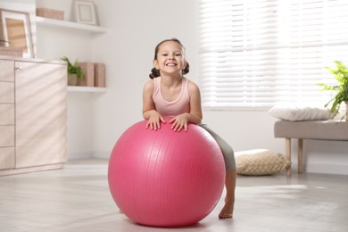 Photo of Cute little girl with fit ball at home