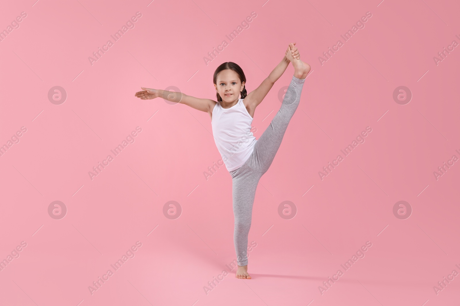 Photo of Cute little girl stretching on pink background