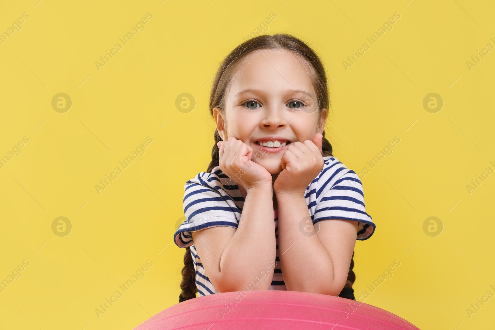 Photo of Cute little girl with fit ball on yellow background