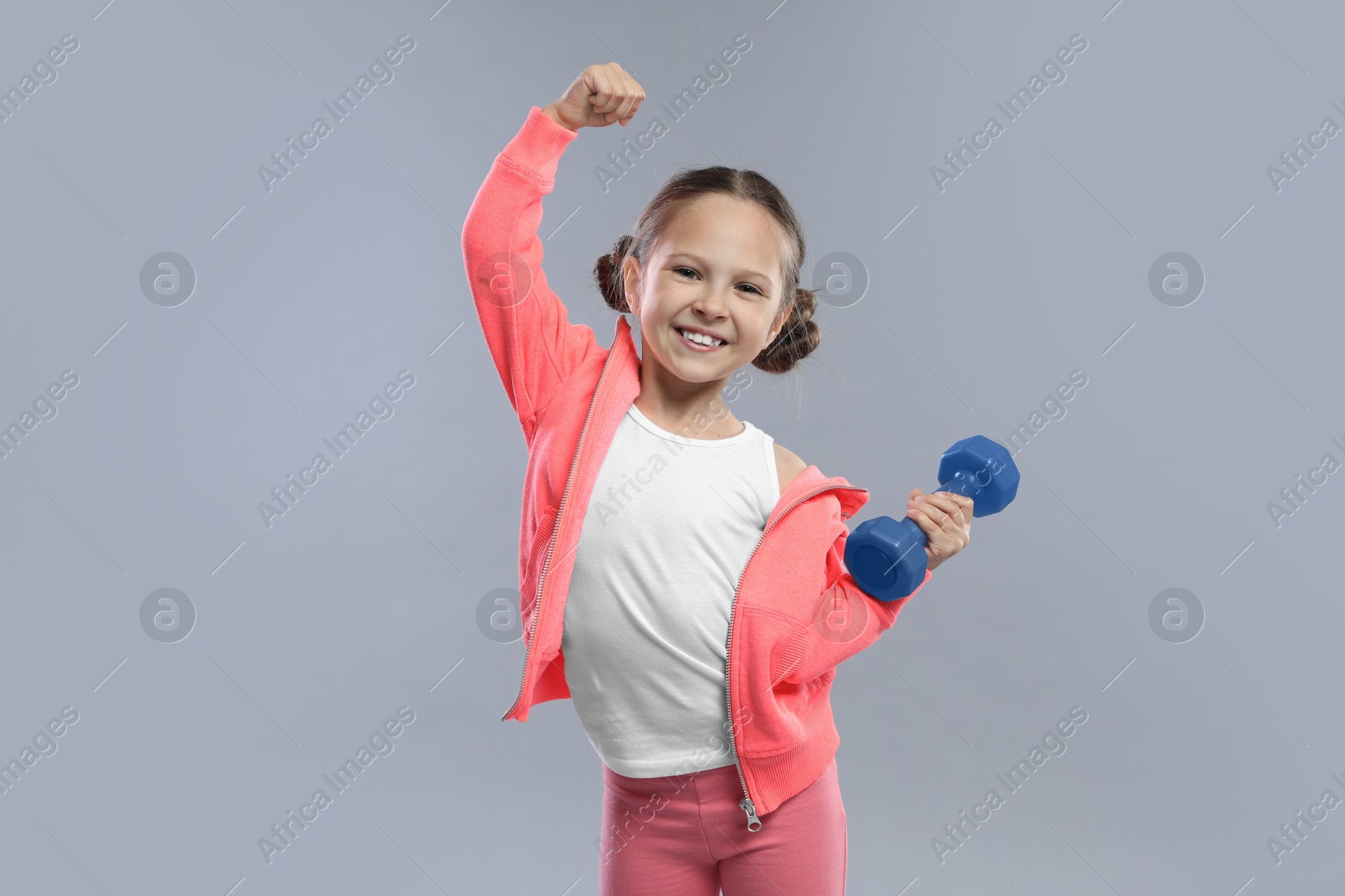 Photo of Cute little girl with dumbbell on grey background