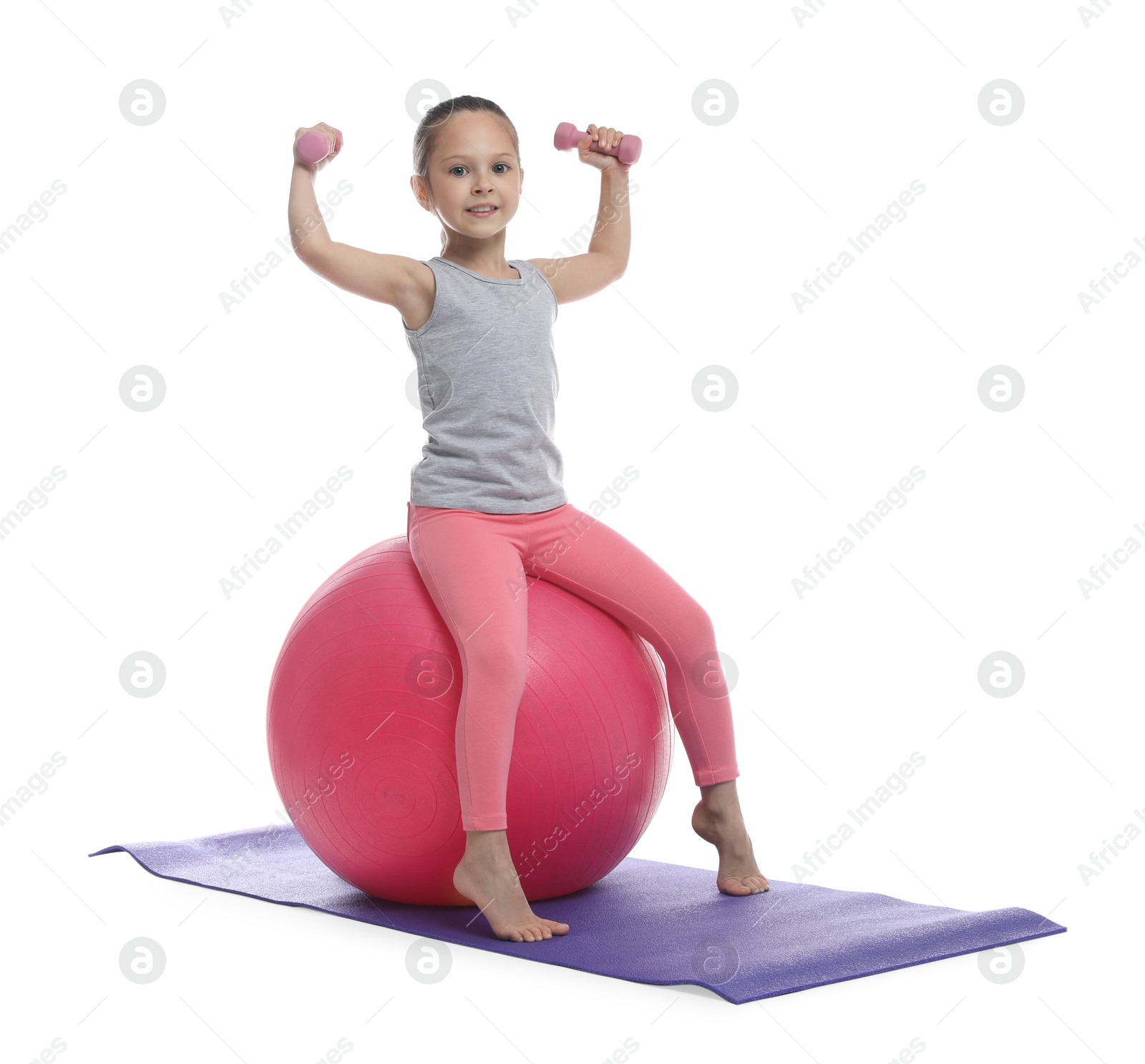 Photo of Cute little girl with dumbbells and fit ball on white background