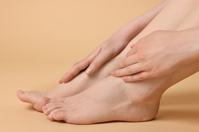 Closeup view of woman`s groomed feet after care procedure on beige background