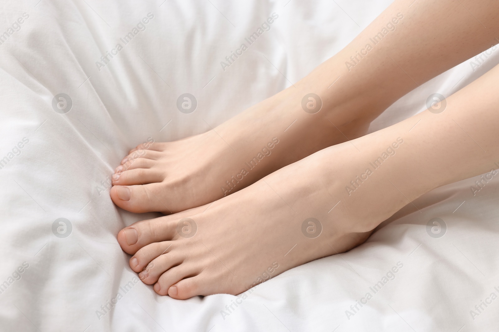 Photo of Closeup view of woman`s groomed feet after care procedure on bed