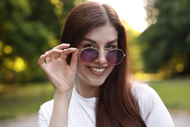 Photo of Portrait of smiling woman in sunglasses outdoors. Spring vibes
