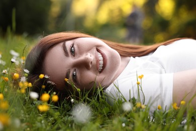 Portrait of smiling woman lying on grass and flowers. Spring vibes