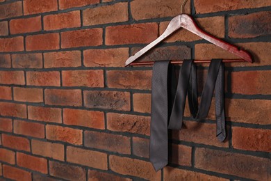 Hanger with black necktie on red brick wall. Space for text