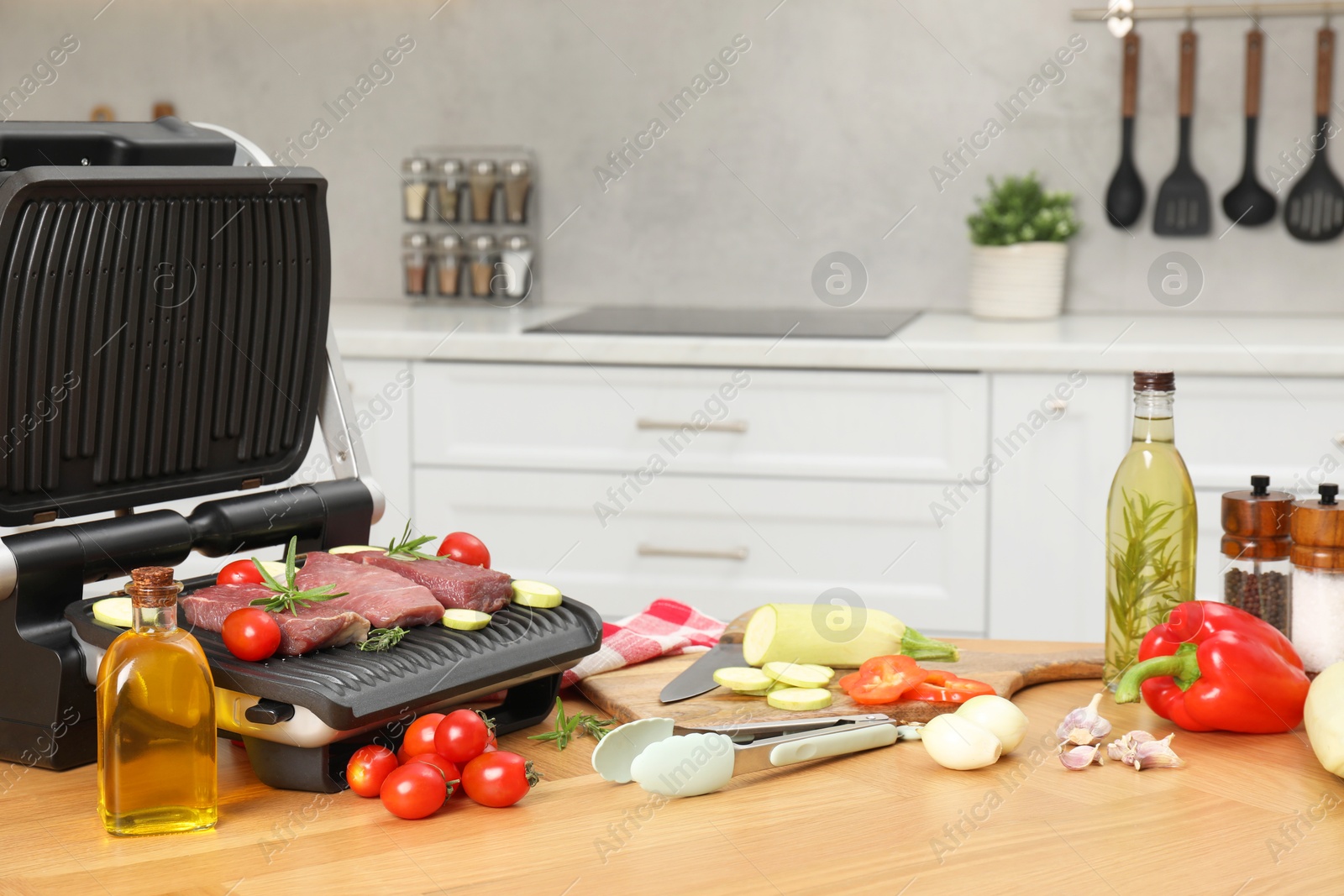 Photo of Electric grill and different products on wooden table