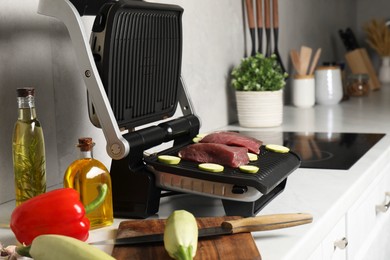 Photo of Electric grill and different products on white wooden table