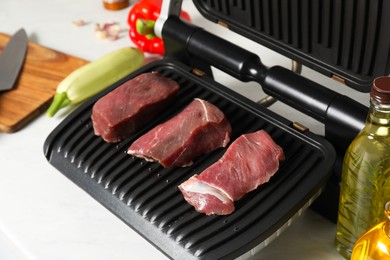 Electric grill and different products on white wooden table, closeup