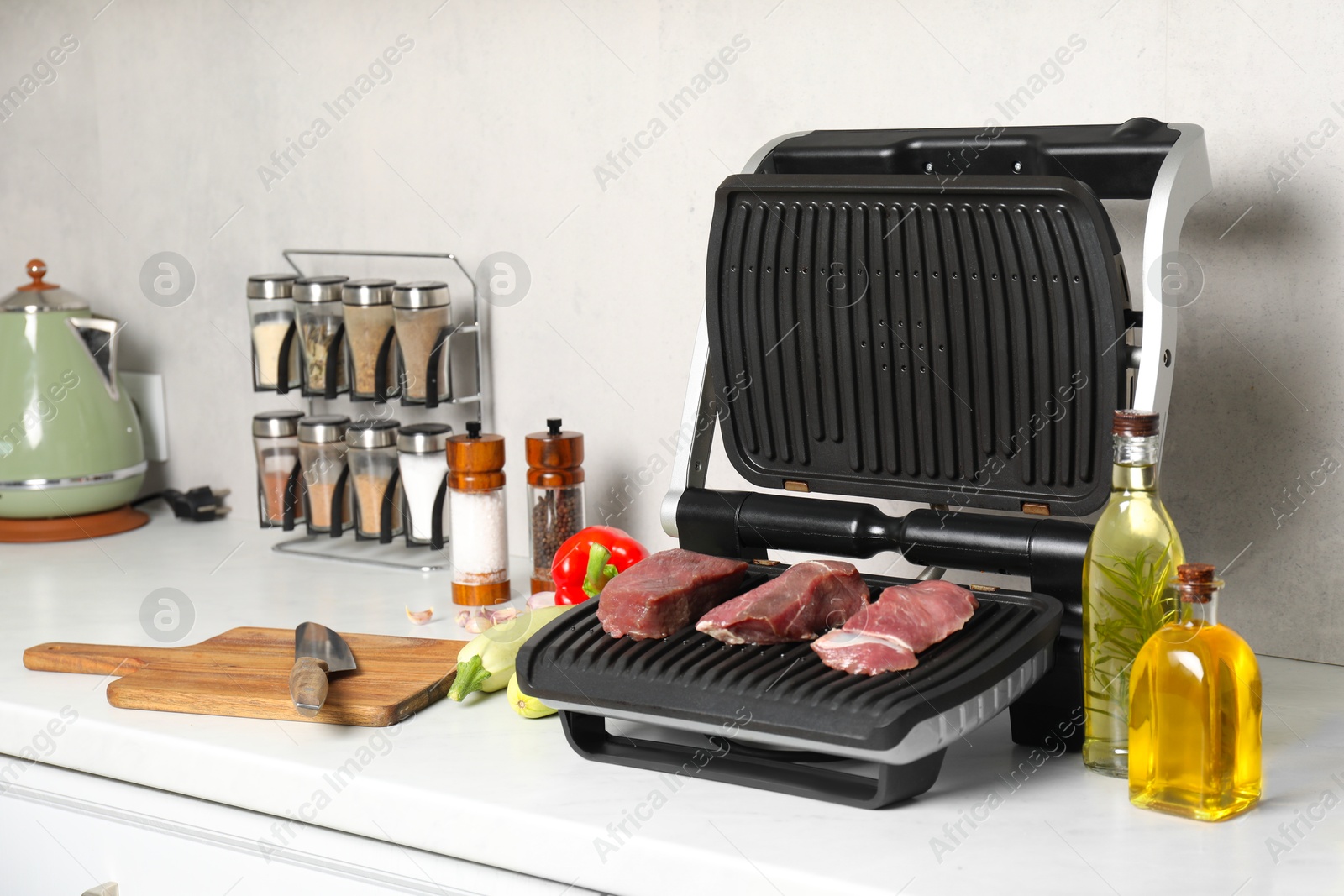 Photo of Electric grill and different products on white wooden table