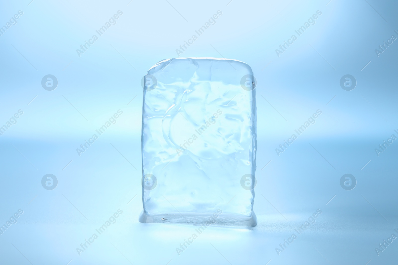 Photo of Cube of clear ice on light blue background
