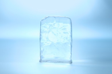 Cube of clear ice on light blue background