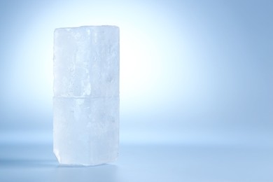 Photo of Blocks of clear ice on light blue background, space for text