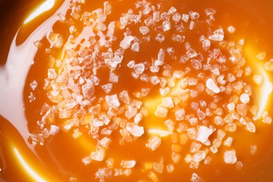Delicious caramel sauce with sea salt as background, top view