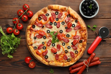 Photo of Tasty pizza, ingredients and cutter on wooden table, top view