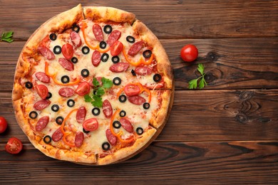 Photo of Tasty pizza with dry smoked sausages, tomatoes, olives, pepper and parsley on wooden table, top view. Space for text