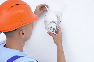 Photo of Technician installing CCTV camera on wall indoors