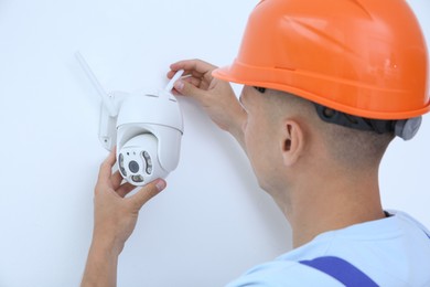 Technician installing CCTV camera on wall indoors