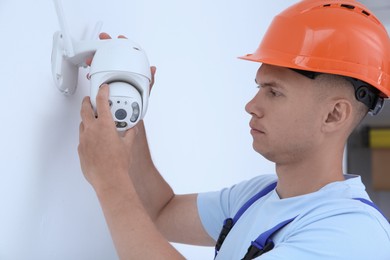 Technician installing CCTV camera on wall indoors