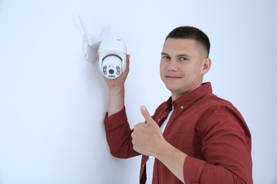 Technician with CCTV camera showing thumb up indoors