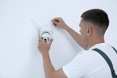 Photo of Technician installing CCTV camera on wall indoors