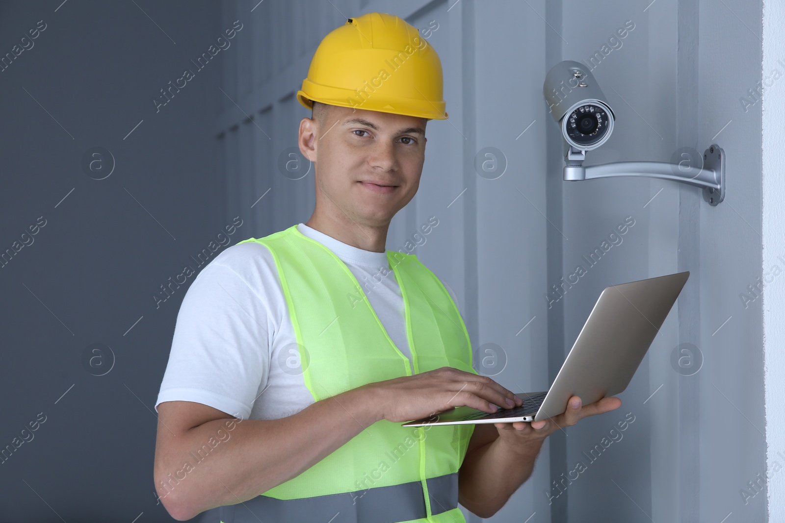 Photo of Technician with laptop installing CCTV camera indoors