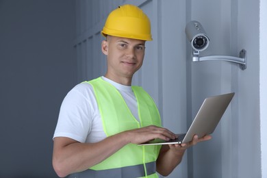 Technician with laptop installing CCTV camera indoors