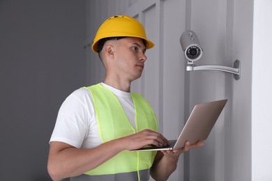 Technician with laptop installing CCTV camera indoors