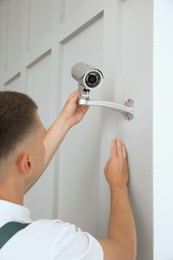 Photo of Technician installing CCTV camera on wall indoors