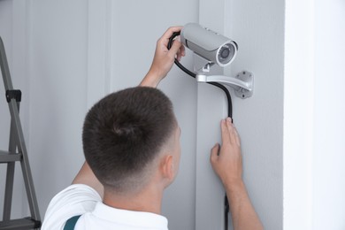 Technician installing CCTV camera on wall indoors