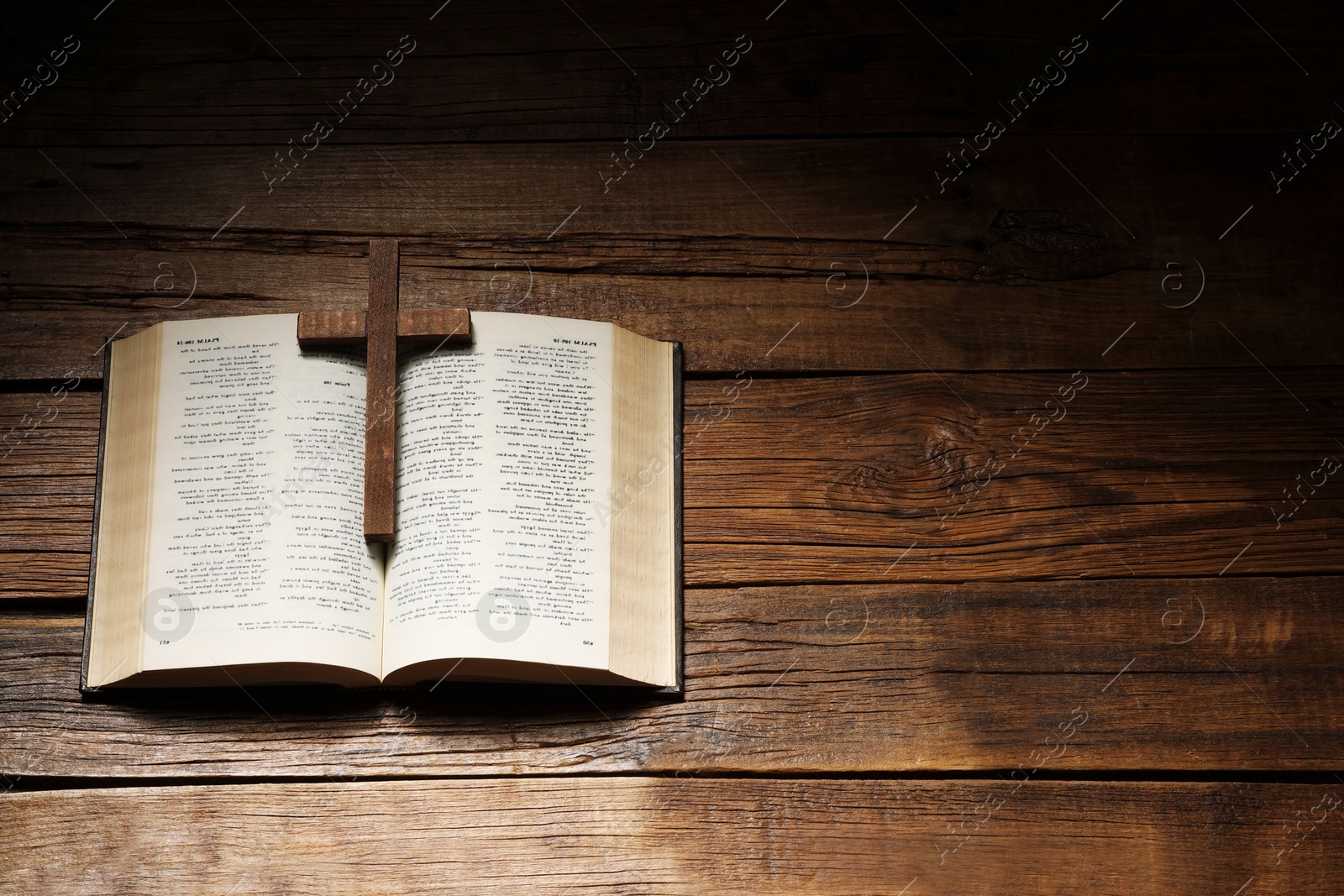 Photo of Bible and cross on wooden table, above view with space for text. Religion of Christianity