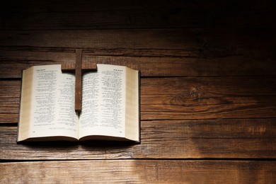 Bible and cross on wooden table, above view with space for text. Religion of Christianity