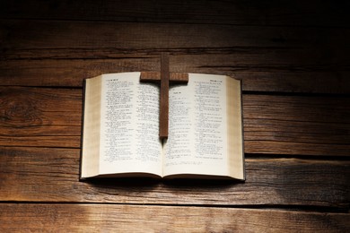 Photo of Bible and cross on wooden table, above view. Religion of Christianity