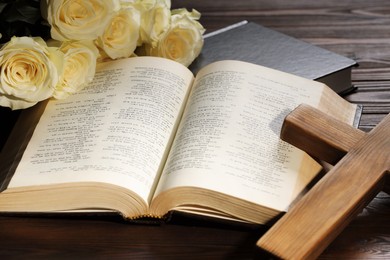 Bibles, cross and roses on wooden table, closeup. Religion of Christianity