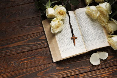 Photo of Bible, cross and roses on wooden table, above view with space for text. Religion of Christianity