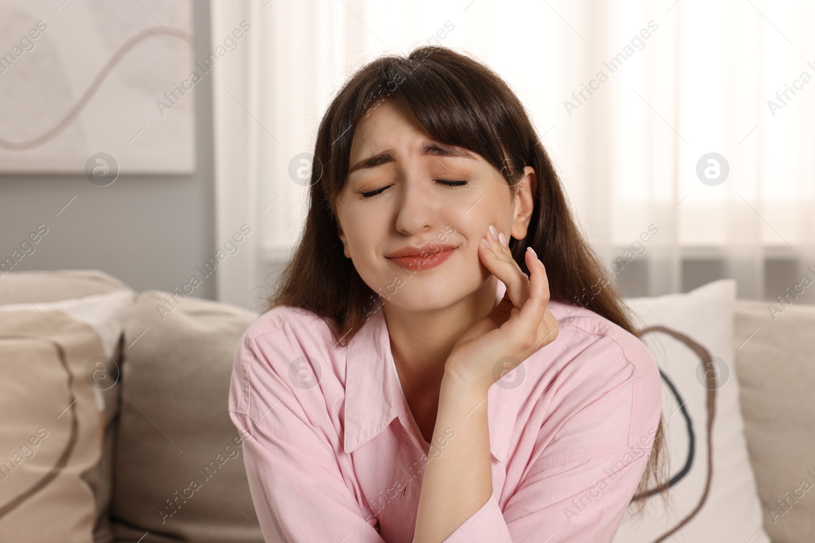 Photo of Upset young woman suffering from toothache indoors