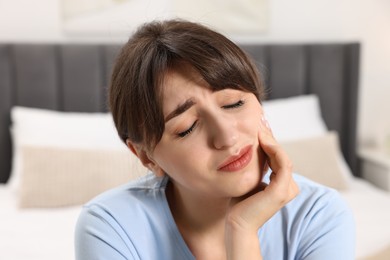 Upset young woman suffering from toothache indoors