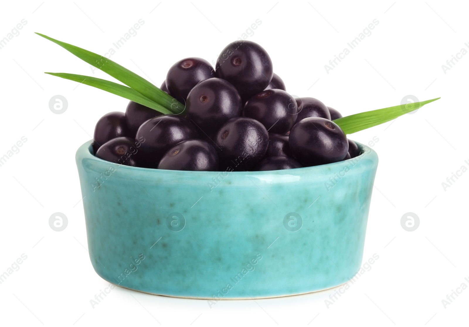 Photo of Fresh ripe acai berries in bowl and green leaves isolated on white