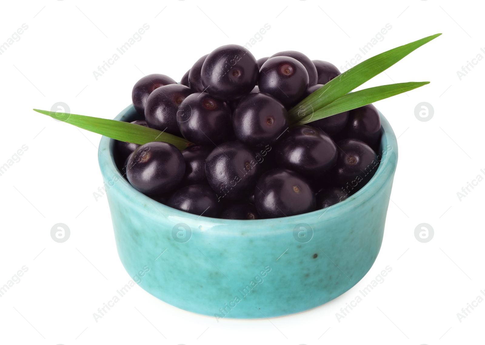 Photo of Fresh ripe acai berries in bowl and green leaves isolated on white