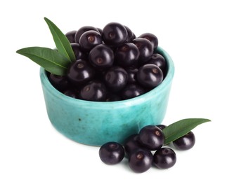 Fresh ripe acai berries in bowl and green leaves isolated on white