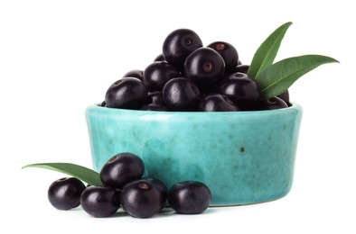 Photo of Fresh ripe acai berries in bowl and green leaves isolated on white