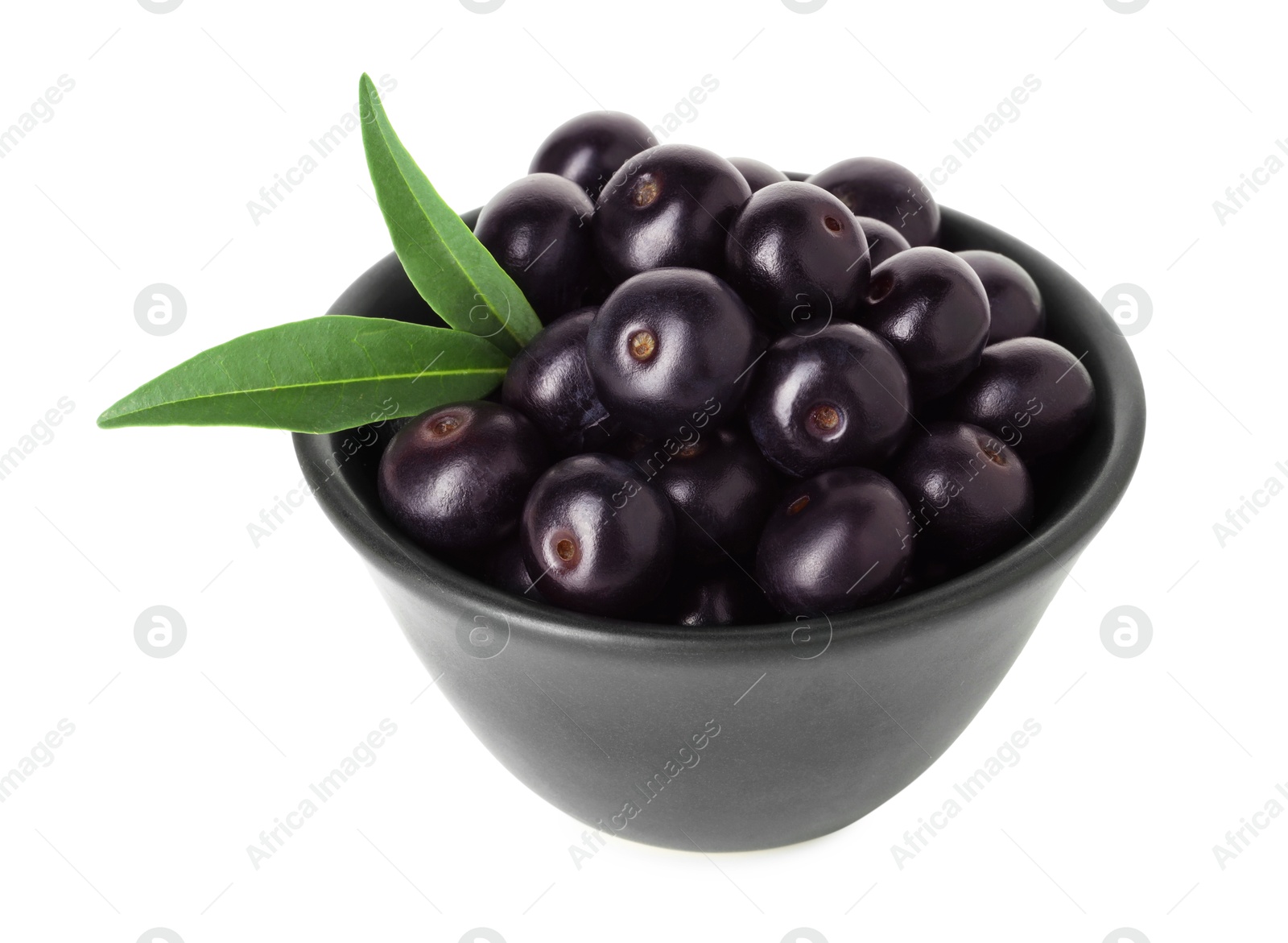 Photo of Fresh ripe acai berries in bowl and green leaves isolated on white