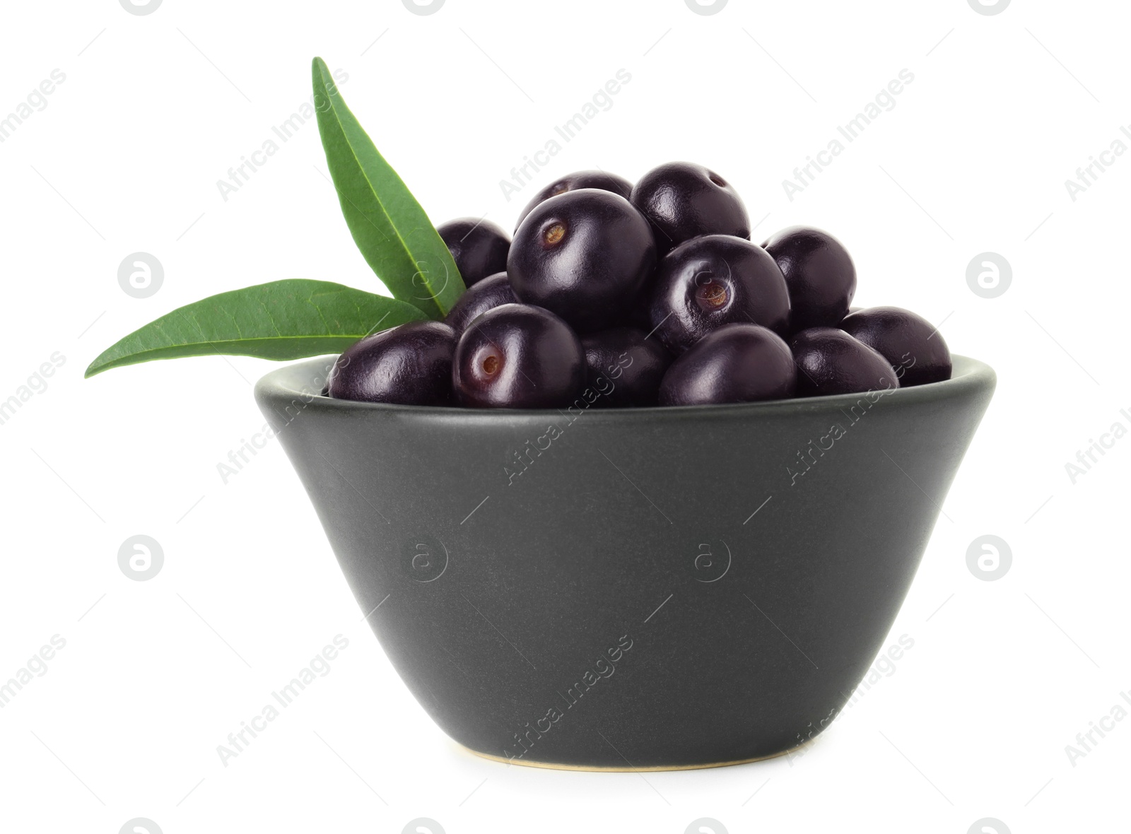 Photo of Fresh ripe acai berries in bowl and green leaves isolated on white