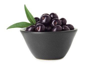 Photo of Fresh ripe acai berries in bowl and green leaves isolated on white