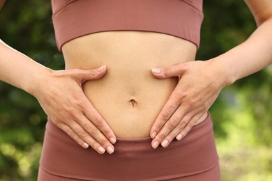 Photo of Healthy digestion. Woman touching her belly outdoors, closeup