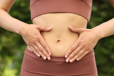 Photo of Healthy digestion. Woman touching her belly outdoors, closeup