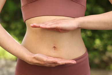 Photo of Healthy digestion. Woman holding something near her belly outdoors, closeup